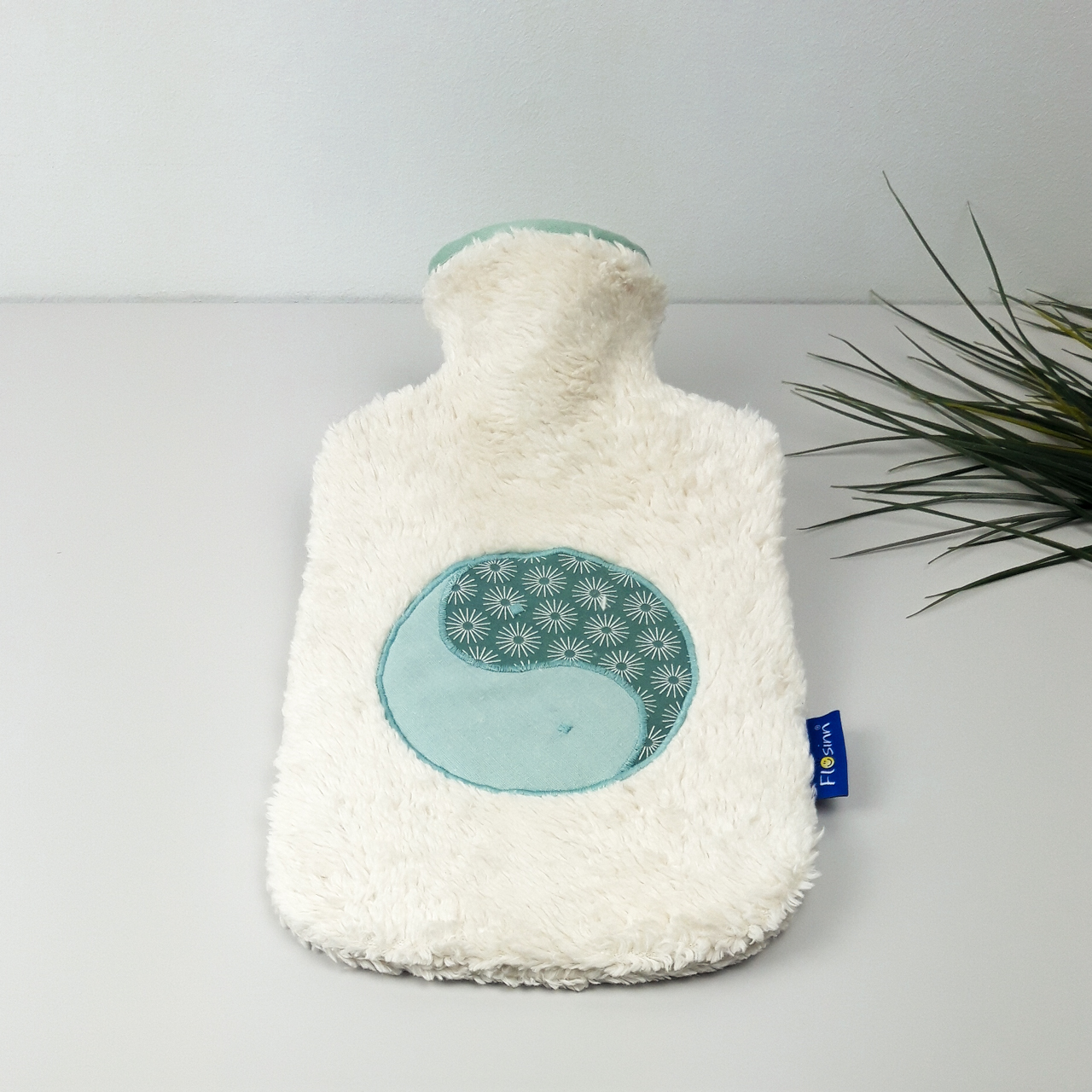 Flosinn Wärmflasche oder Bettflasche mit Bezug aus Bio Teddyplüsch mit einer Yin Yang Applikation in Mint Salbei