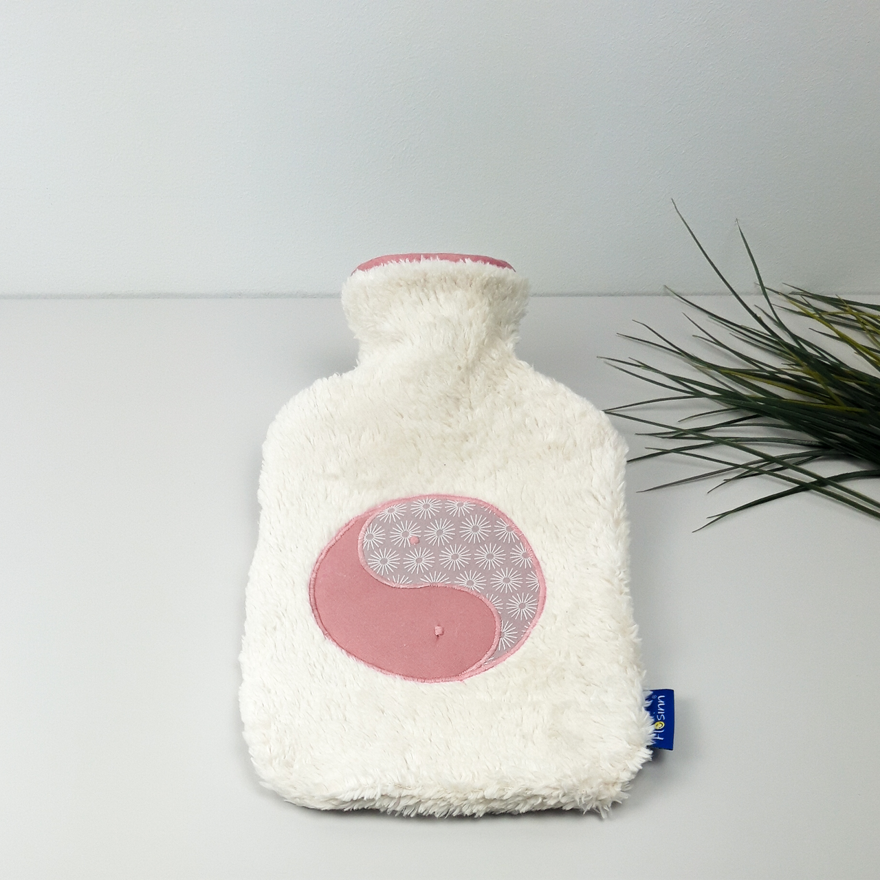 Flosinn Wärmflasche oder Bettflasche mit Bezug aus Bio Teddyplüsch mit einer Yin Yang Applikation in Rosé