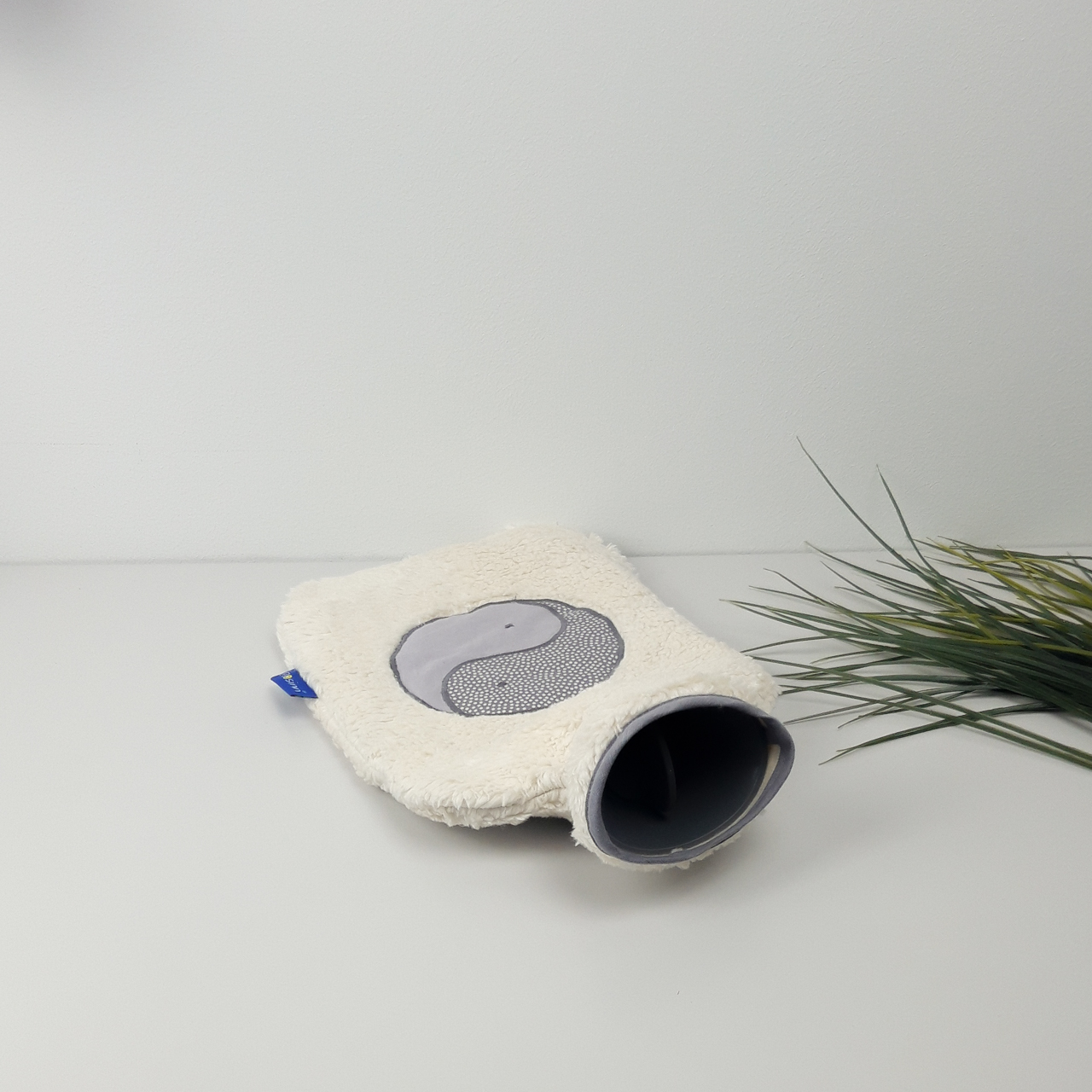 Flosinn Wärmflasche oder Bettflasche mit Bezug aus Bio Teddyplüsch mit einer Yin Yang Applikation in Grau Öffnung